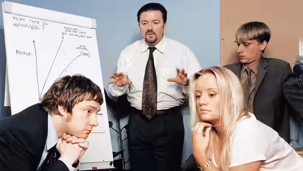 David Brent (Ricky Gervais) explaining to colleagues beside a whiteboard