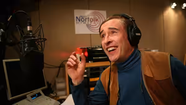 Alan Partridge (Steve Coogan) speaks into a microphone in a radio studio