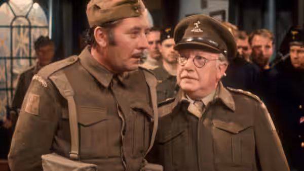 Captain Mainwaring in conversation with Private Walker inside the hall
