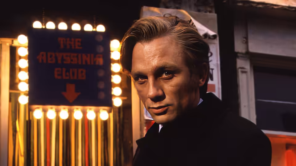 Geordie Peacock (Daniel Craig) stands outside The Abyssinia Club at night