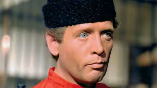 Number Six (Patrick McGoohan) in close-up wearing a red shirt and black hat