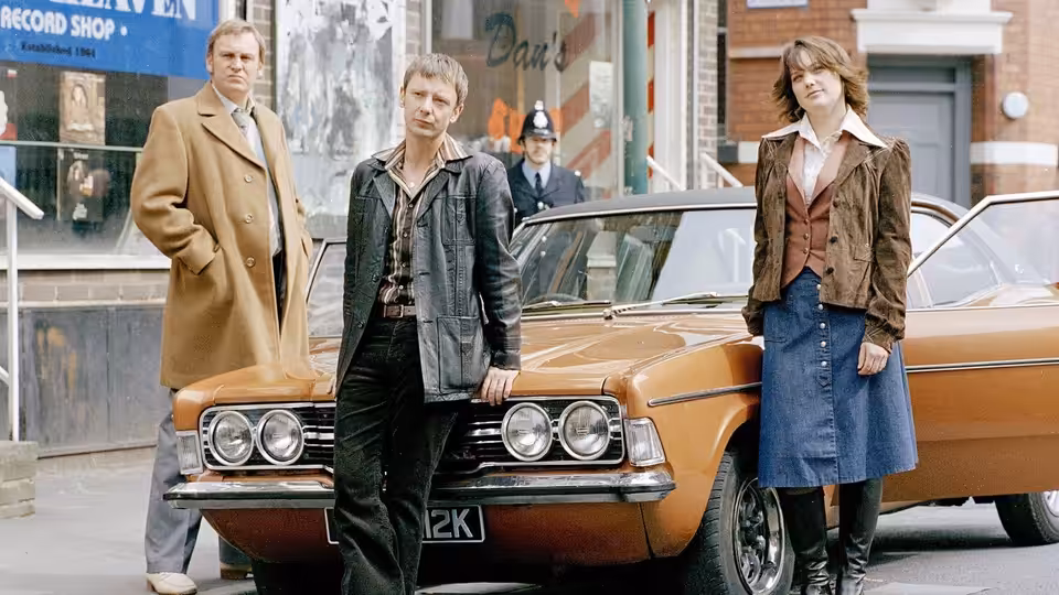 Gene Hunt (Philip Glenister), Sam Tyler (John Simm) and Annie Cartwright (Liz White) beside an orange car