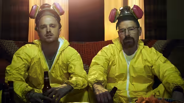 Jesse Pinkman (Aaron Paul) and Walter White (Bryan Cranston) in yellow hazmat suits on a sofa