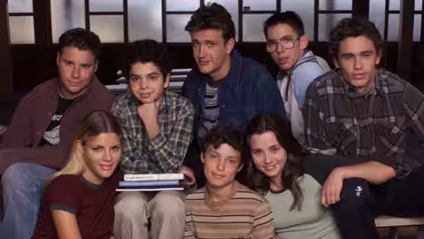 Eight students gathered on benches in a school hallway