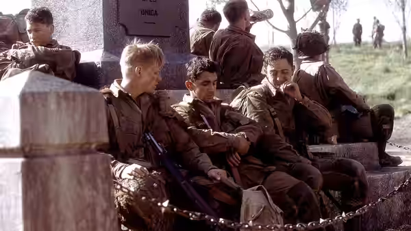 Soldiers resting on stone steps beside a monument outdoors