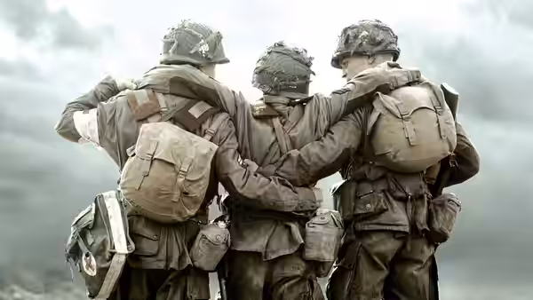 Three soldiers with arms around each other walking through a field
