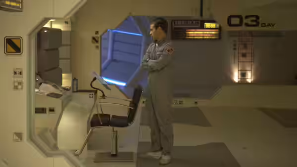 Sam Bell (Sam Rockwell) standing with arms crossed in lunar bay 03