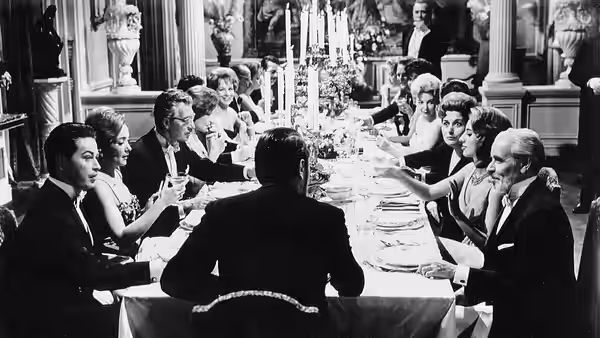 Guests sit around a long dining table in an ornate room