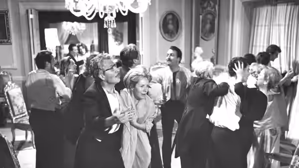 Well-dressed guests mingle in a crowded mansion drawing room