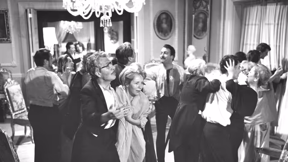 Well-dressed guests mingle in a crowded mansion drawing room
