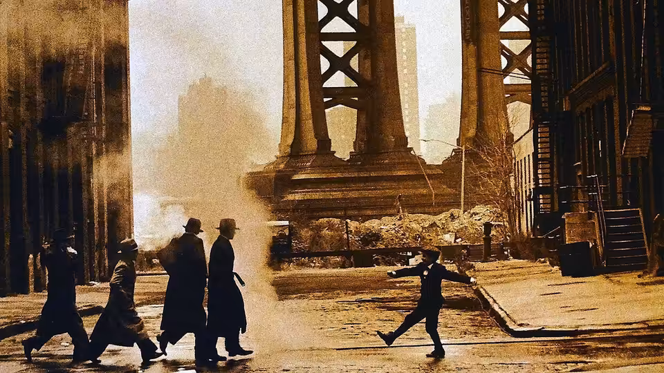 Men in coats and hats walking on a street under a large bridge, one gesturing