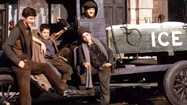 Young men posing around an ice truck parked on a city street
