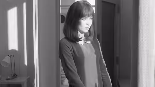 Natacha von Braun (Anna Karina) stands alone beside an open doorway
