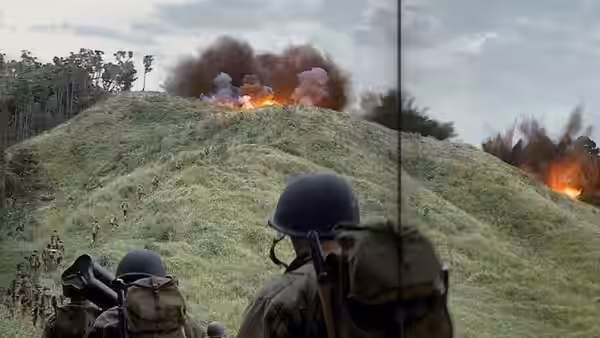 Soldiers advancing up a grassy hill under artillery fire
