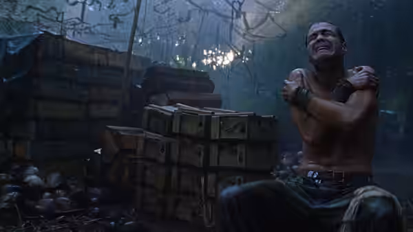 A shirtless soldier sitting among crates in the rain