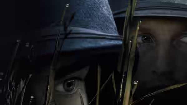 Two soldiers peering through tall grass with helmets on