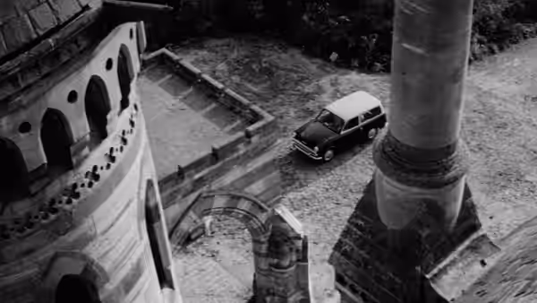 A car sits in the courtyard outside a sprawling mansion