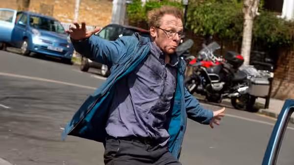 Neil (Simon Pegg) gesturing with arms outstretched on a city street