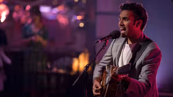 Jack Malik (Himesh Patel) singing and playing guitar on a purple-lit stage