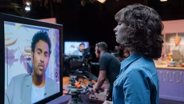 Ellie Appleton (Lily James) watching Jack Malik on a television studio monitor