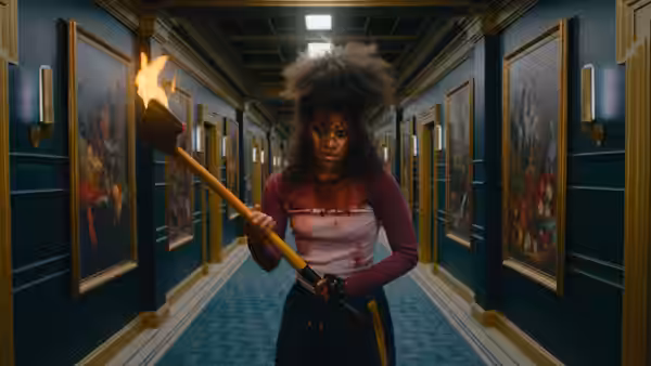 Asia Reaves (Zazie Beetz) grips a flaming weapon in a framed hallway