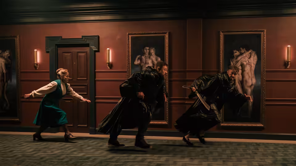 Asia Reaves (Zazie Beetz) fights black-robed figures in a paneled hallway