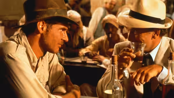Indiana Jones (Harrison Ford) facing Dr. René Belloq (Paul Freeman) across table