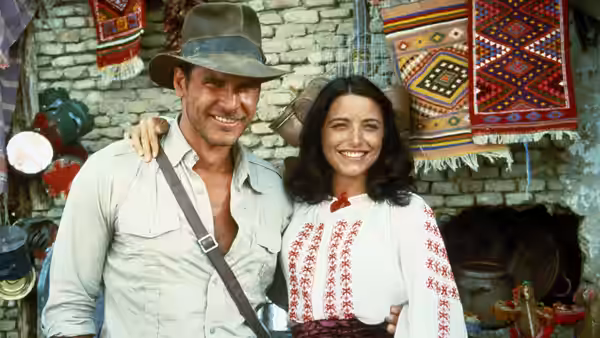 Indiana Jones (Harrison Ford) with arm around Marion Ravenwood (Karen Allen) in market