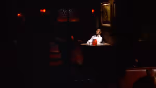 A woman sits alone at a table in a dark club