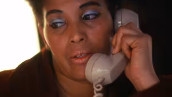 A woman speaks on a telephone, looking to the side