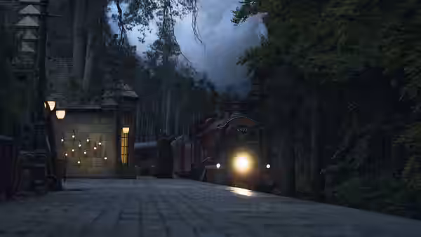 A train approaches a station platform bordered by dark trees and stone buildings