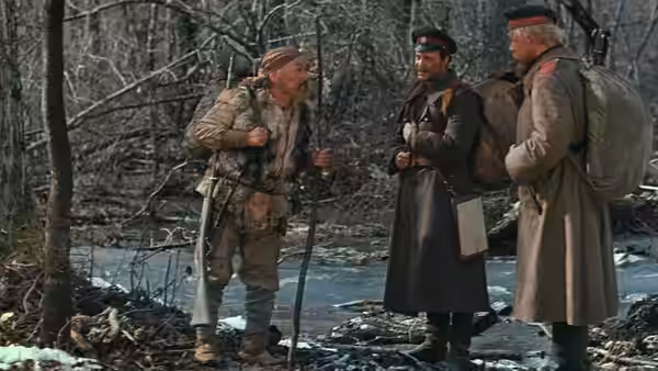 Dersu Uzala (Maksim Munzuk) talks with Arsenev (Yury Solomin) beside a forest stream