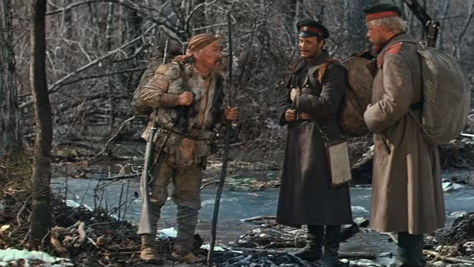 Dersu Uzala (Maksim Munzuk) talks with Arsenev (Yury Solomin) beside a forest stream