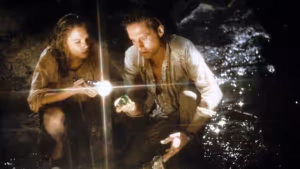 Joan Wilder (Kathleen Turner) and Jack Colton (Michael Douglas) explore a dark cave by flashlight
