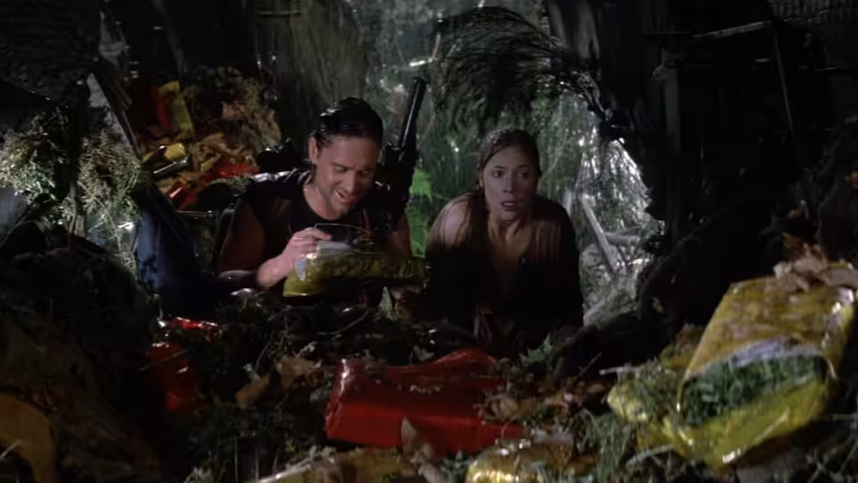 Jack Colton (Michael Douglas) and Joan Wilder (Kathleen Turner) crouch amid wreckage in the jungle