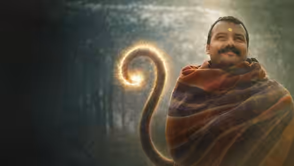 Neem Karoli Baba (Shobhinaw Satyaa) stands wrapped in a shawl beside a glowing curled tail