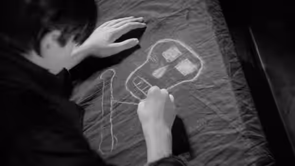 A boy draws a map on paper at a desk