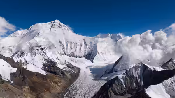 Snow-covered Himalayan peaks and glaciers rise above a broad mountain valley