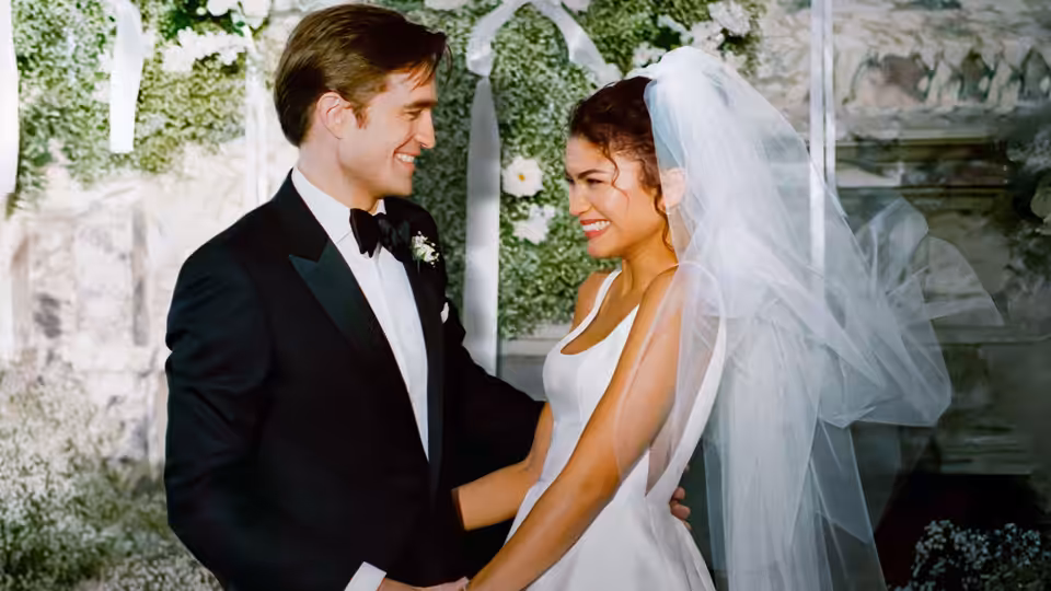 Charlie (Robert Pattinson) and Emma (Zendaya) smiling at each other in wedding attire