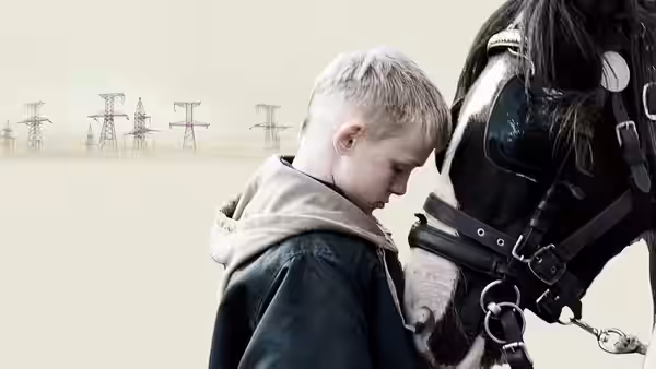 Blond boy bows his head beside the muzzle of a black horse