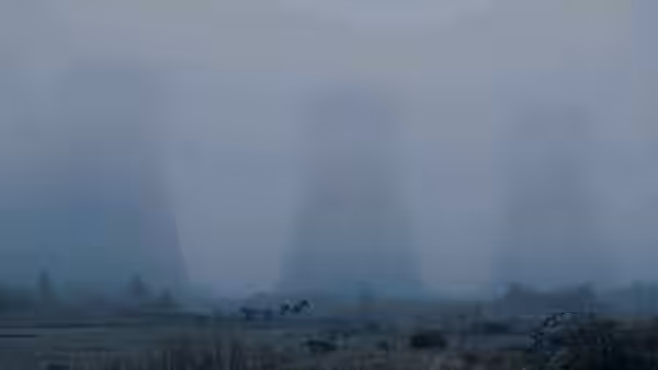 Horse and cart cross a misty field past distant cooling towers