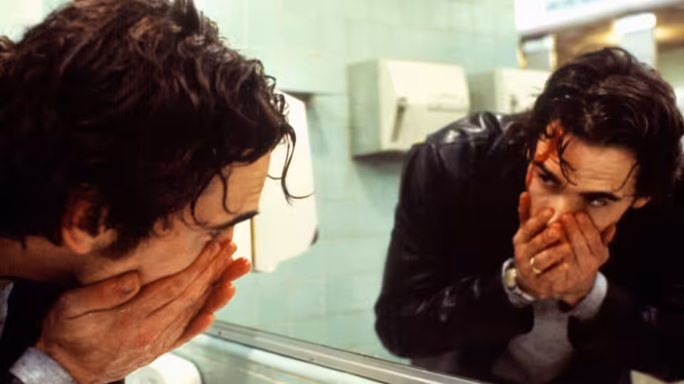 Bob (Matt Dillon) washes blood from his face while looking into a bathroom mirror