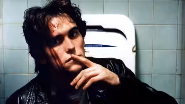 Rick (James LeGros) rests a finger against his lips in a tiled bathroom