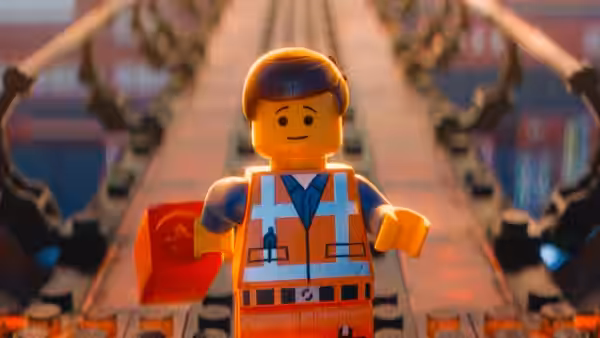 Emmet Brickowski (Chris Pratt) stands on train tracks holding a red toolbox