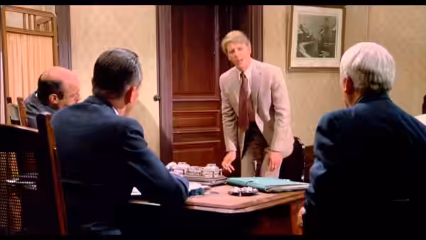The Jackal (Edward Fox) stands at a table speaking with three seated men