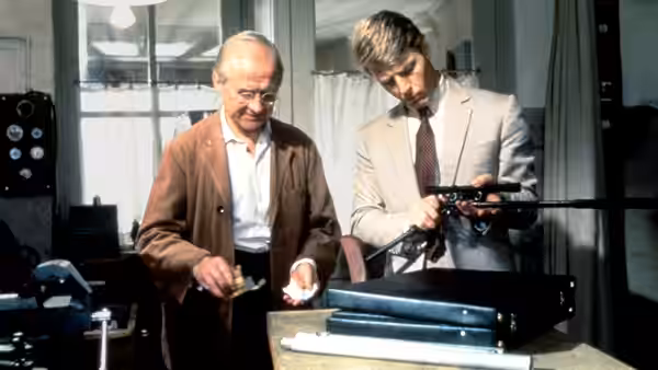 The Jackal (Edward Fox) inspects a rifle with the gunsmith (Cyril Cusack)