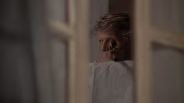The Jackal (Edward Fox) peers through a narrow gap holding an object