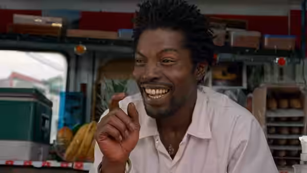 Ghost Dog (Forest Whitaker) smiling and gesturing at an outdoor market