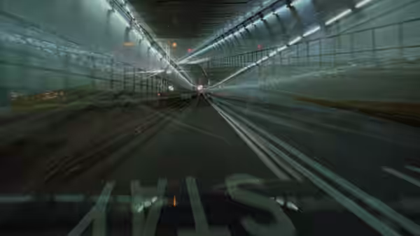 view from inside a car driving through a long illuminated tunnel
