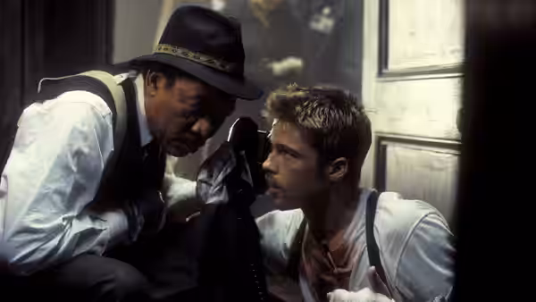 Somerset (Morgan Freeman) leans close to injured Mills (Brad Pitt) in a doorway